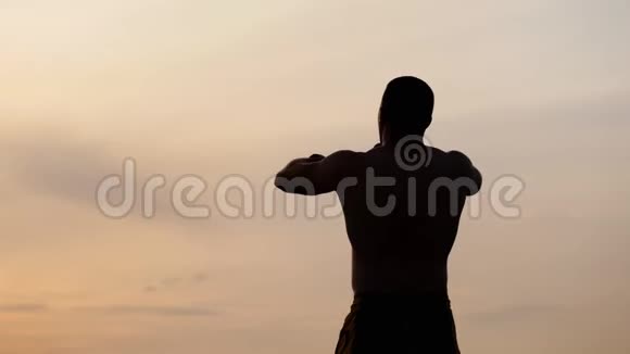 运动男子的剪影裸露的躯干摆姿势显示他的肌肉对抗天空在日落体育健康和视频的预览图