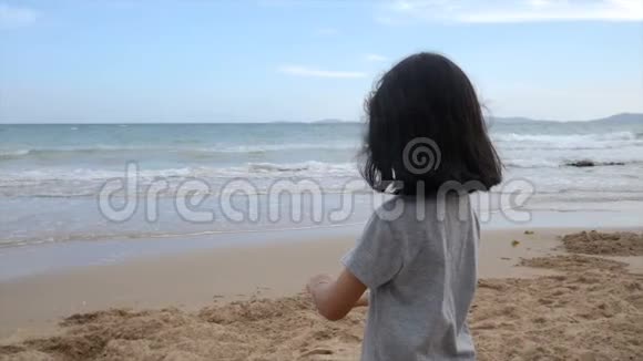 亚洲小女孩在沙滩上玩自然海浪海岸暑假概念视频的预览图