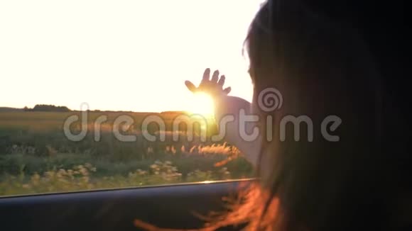 年轻漂亮的白种人女人坐在车里手在日落时分的空中嬉戏视频的预览图