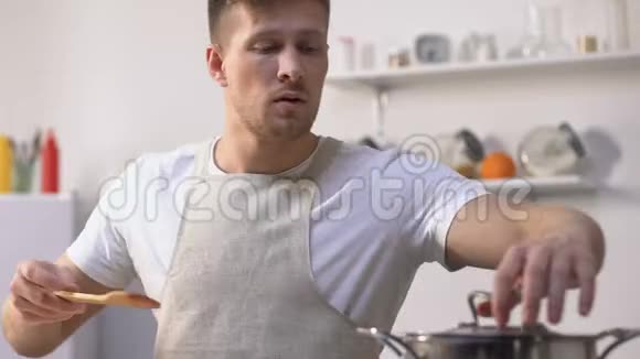 穿着围裙做饭的帅哥在平底锅里搅拌食材尝试着吃饭视频的预览图