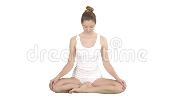美丽的年轻女子瑜伽上升她的眼睛相机和微笑坐在莲花姿态的白色背景视频的预览图