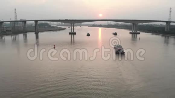 一架无人机慢慢地飞过一条河许多货船沿着这条河航行视频的预览图