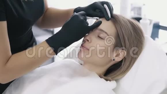 特写女人她的脸和美容医生她的手用注射器做面部美容注射视频的预览图