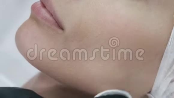 化妆过程中女性面部的特写医生用棉盘消毒病人皮肤视频的预览图