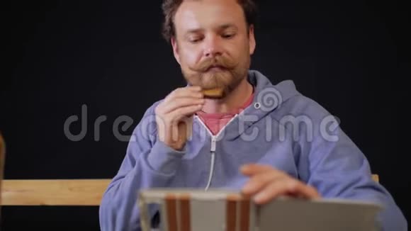 一个留胡子的人坐在桌边手里拿着一瓶啤酒视频的预览图