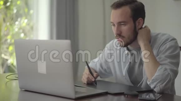 成功留胡子的家伙用图形平板电脑绘制笔记本电脑男性手绘三维动画制作视频的预览图