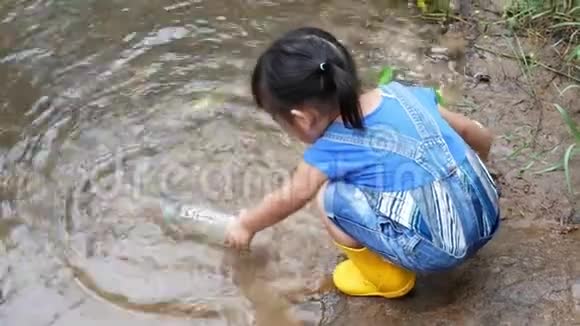 亚洲小孩正在捡起漂浮在河岸上的塑料垃圾环境保护概念视频的预览图