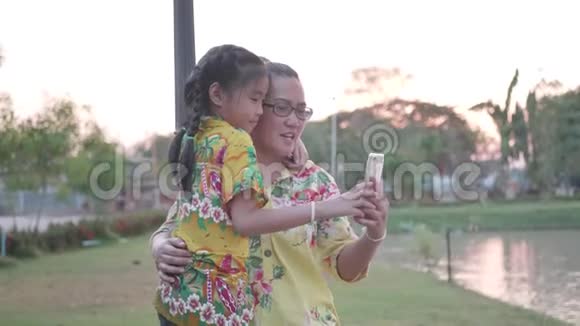 亚洲家庭使用智能手机在公共公园视频的预览图