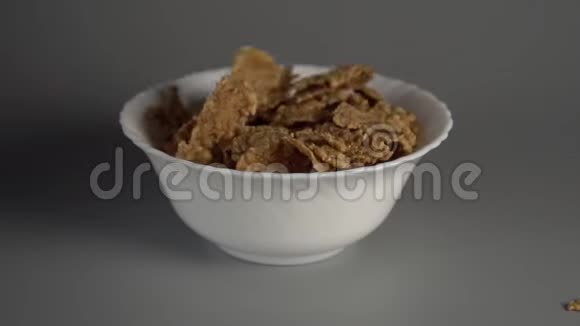 燕麦片慢慢地落入白色的盘子里飞向不同的方向视频的预览图