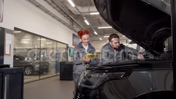 两个专业的汽车机械师检查一辆汽车的发动机做笔记视频的预览图