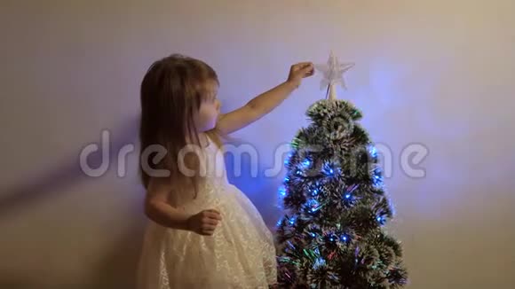 儿童圣诞假期快乐概念孩子在节日树上检查一颗圣诞星小女孩在附近玩耍视频的预览图
