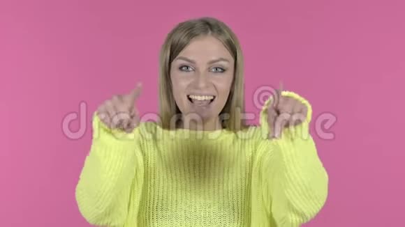 开朗的少女指指点点和邀请粉色背景视频的预览图