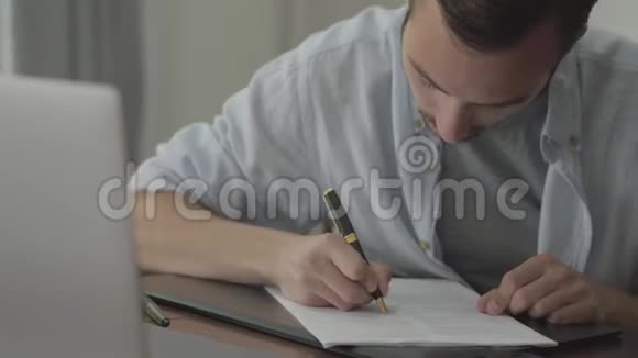 坐在桌子旁批改他的论文的人在家里写在纸上职业概念作家文案编辑视频的预览图
