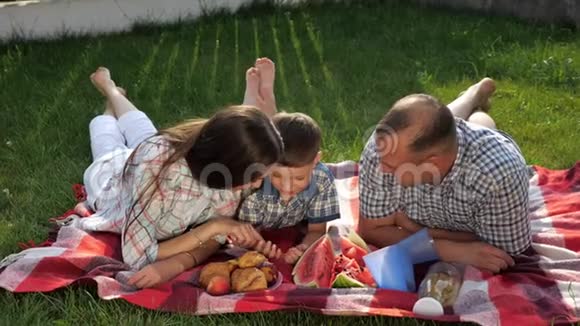 快乐的家庭成员趴在野餐的红毯子上视频的预览图