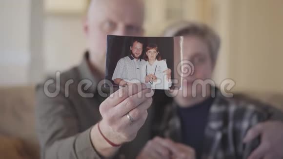 当男人和女人很小的时候一对年长的夫妇向镜头展示照片的肖像登录未定级视频的预览图