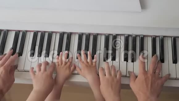 钢琴键盘顶视手的母婴播放音乐家庭团结观念视频的预览图