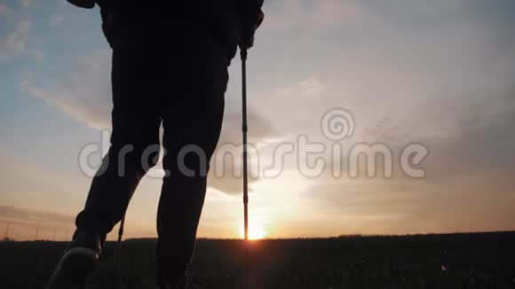 剪影徒步旅行者与背包跟踪和徒步杆在日落的背景与大自然独处健康视频的预览图