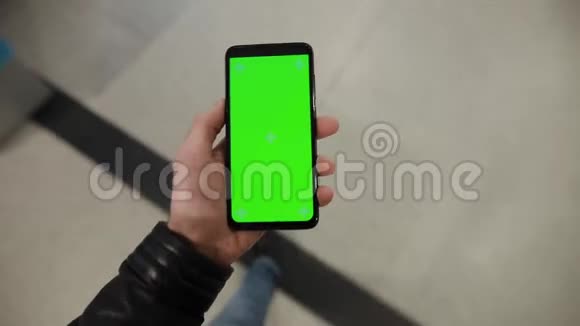 在商场自动扶梯中使用绿色屏幕智能手机的男性视频的预览图