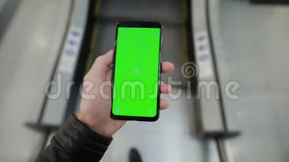 在商场自动扶梯中使用绿色屏幕智能手机的男性视频的预览图
