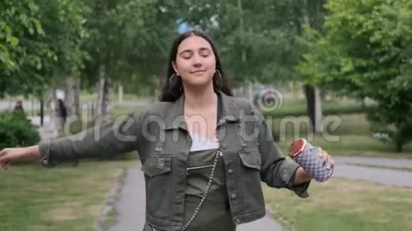心情愉快的时髦女孩走在街上用便携式扬声器听音乐跳舞视频的预览图