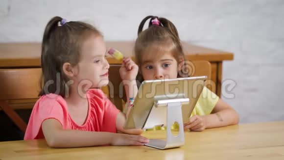 两个小女孩吃冰淇淋看平板电脑上的卡通片视频的预览图