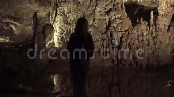 旅游女孩独自站在石洞里的一条小山河的水泥岸上视频的预览图