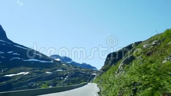 在挪威的一条高山公路上驾驶汽车山上有雪从前挡风玻璃上可以看到视频的预览图