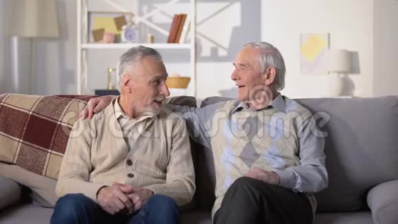 两个老朋友在家里坐在沙发上嬉笑打闹孩子气视频的预览图