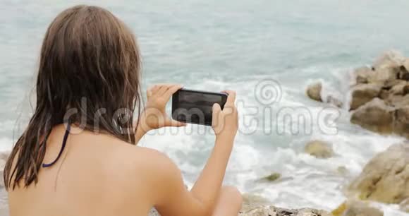 女孩在智能手机上拍摄风暴海视频的预览图