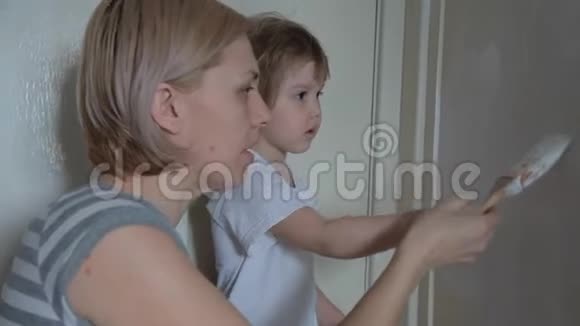 一个小可爱的女孩用颜料画一堵墙用画笔和微笑吻他妈妈和红猫视频的预览图