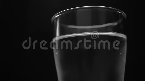 将冰块倒入装有水的玻璃杯中在黑色背景下隔离视频的预览图