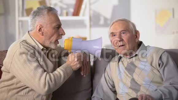 老年男性用扩音器与失聪的老朋友交谈健康问题特写视频的预览图
