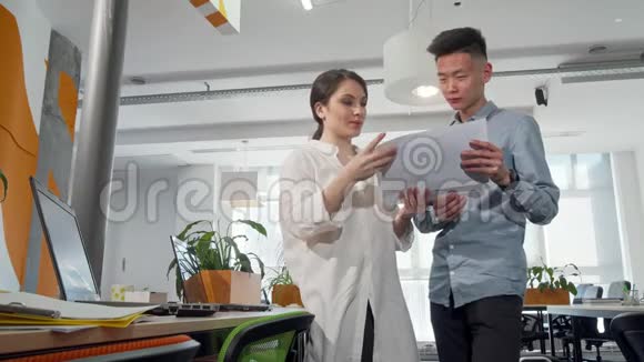 两位年轻的企业家在办公室里看报纸视频的预览图