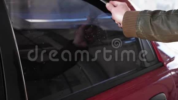 一个穿着皮夹克的人在洗车后擦拭玻璃的手视频的预览图