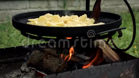 在烤架上用铸铁锅烤土豆在明火上放有土豆的铸铁煎锅视频的预览图