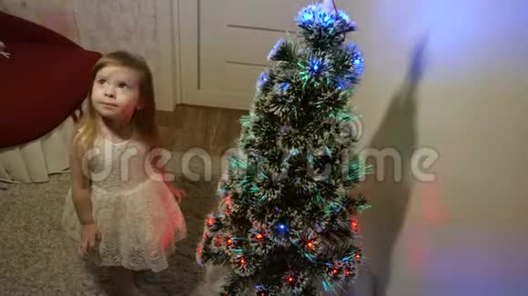 快乐的童年概念小孩子在儿童房的圣诞树旁玩耍美丽的人工圣诞树视频的预览图
