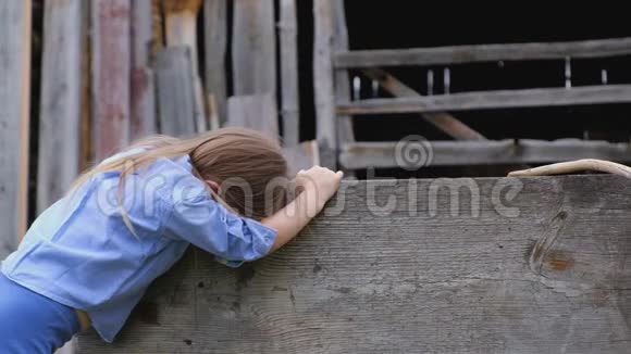 穿着蓝色衣服的悲伤的小女孩堆在木栅栏上视频的预览图