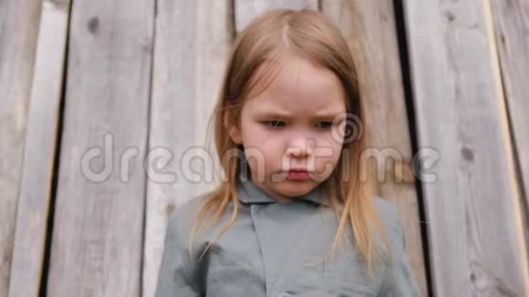 穿着灰色亚麻布夹克的可爱的小女孩在灰色木栅栏上摆姿势视频的预览图