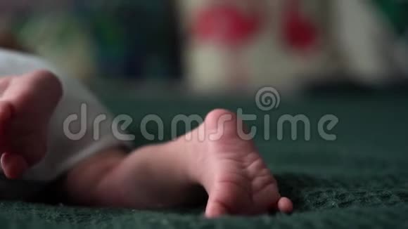 小可爱的小脚宝宝小新生儿脚特写躺在深绿色的毯子上穿着白色的连衣裙或连衣裙视频的预览图