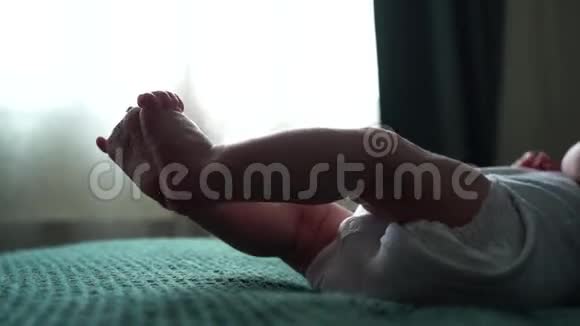 小可爱的小脚宝宝小新生儿脚特写躺在深绿色的毯子上穿着白色的连衣裙或连衣裙视频的预览图