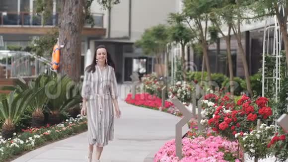优雅的女人穿着长裙穿过城市公园视频的预览图
