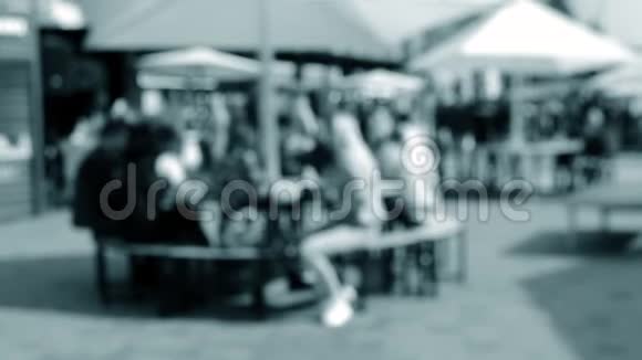 人们在镇上阳光明媚的日子里坐在桌子旁撑着雨伞视频的预览图