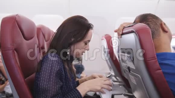飞机上的女人吐在纸袋里乘坐飞行飞机的旅行者会感到恶心在飞行中的恶心乘客视频的预览图