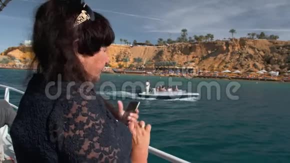 一位年长的女性快乐的成年游客在游艇上休息在游艇上拍摄一艘帆船船上的游客未被认出视频的预览图