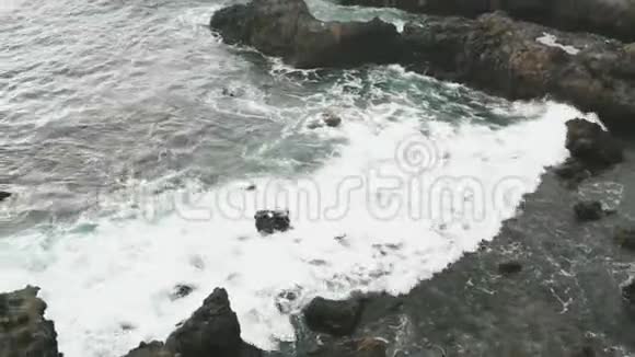 在海洋海岸的冰冻熔岩的空中视野一个由火山喷发而来的海滩靠近天然的水中的岩石视频的预览图