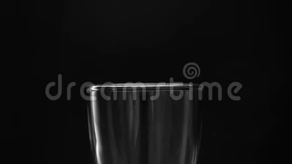 特写手拿塑料瓶和倒入水的玻璃隔离在黑色背景上视频的预览图