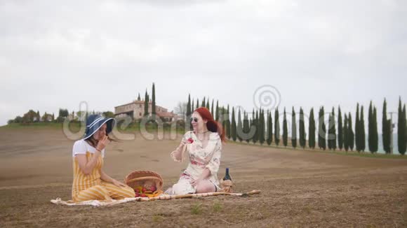 两个女人在野餐和吃水果托斯卡纳柏树路视频的预览图