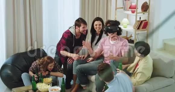 一群笑容可掬有魅力的成年朋友他们多民族在一起玩得很开心其中一个人在虚拟现实中玩视频的预览图