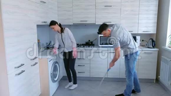夫妻俩一起在厨房打扫卫生男人用拖把洗地板女人擦家具视频的预览图