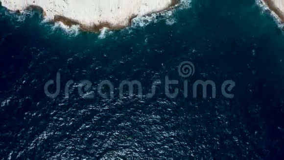 从空中无人机拍摄的海浪冲击到岩石海岸线的俯视图视频的预览图